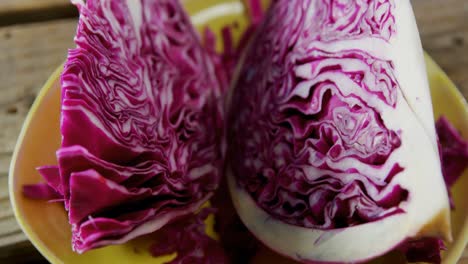 sliced red cabbage in plate on wooden table 4k