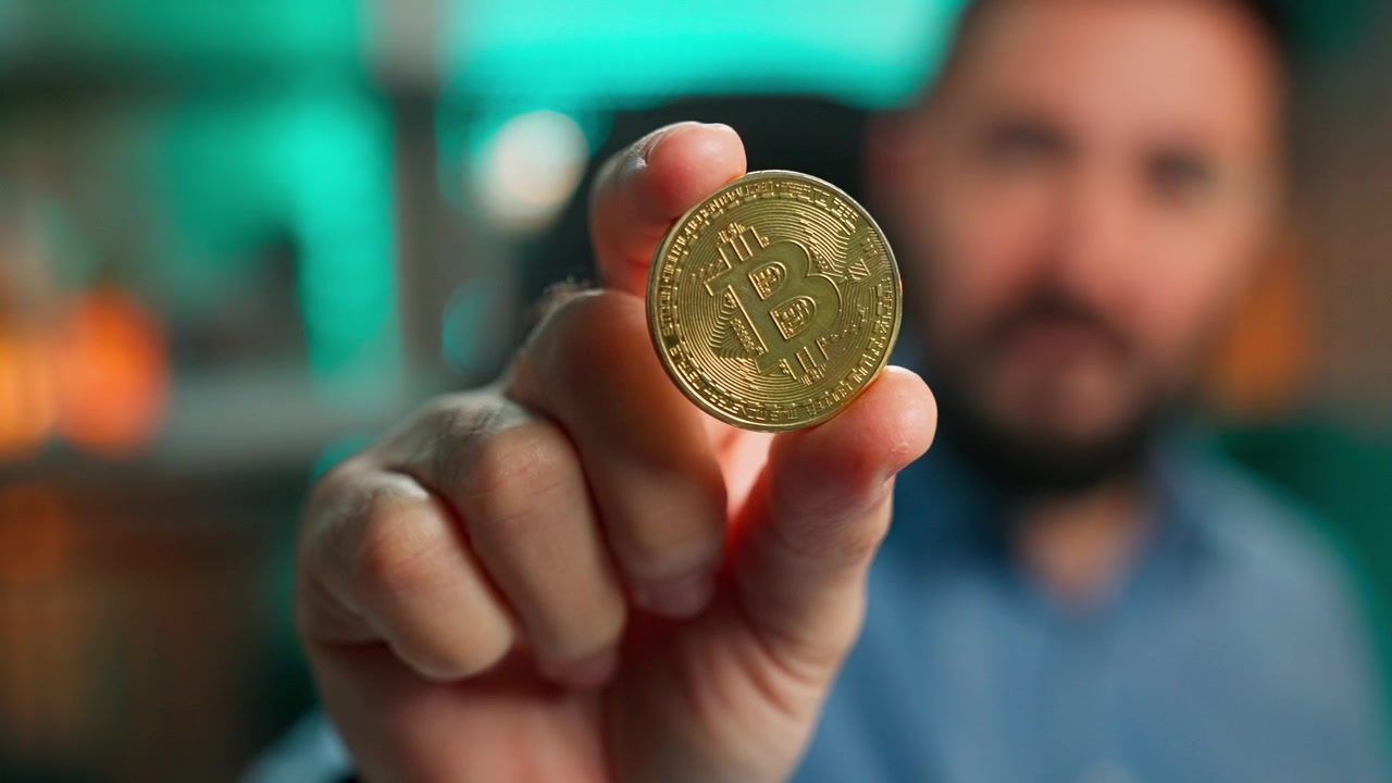 Uomo che tiene in mano una moneta di criptovaluta Bitcoin dorata