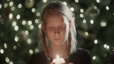 Portrait-of-a-child-with-a-candle-in-his-hands.-Standing-on-the-background-of-the-Christmas-tree