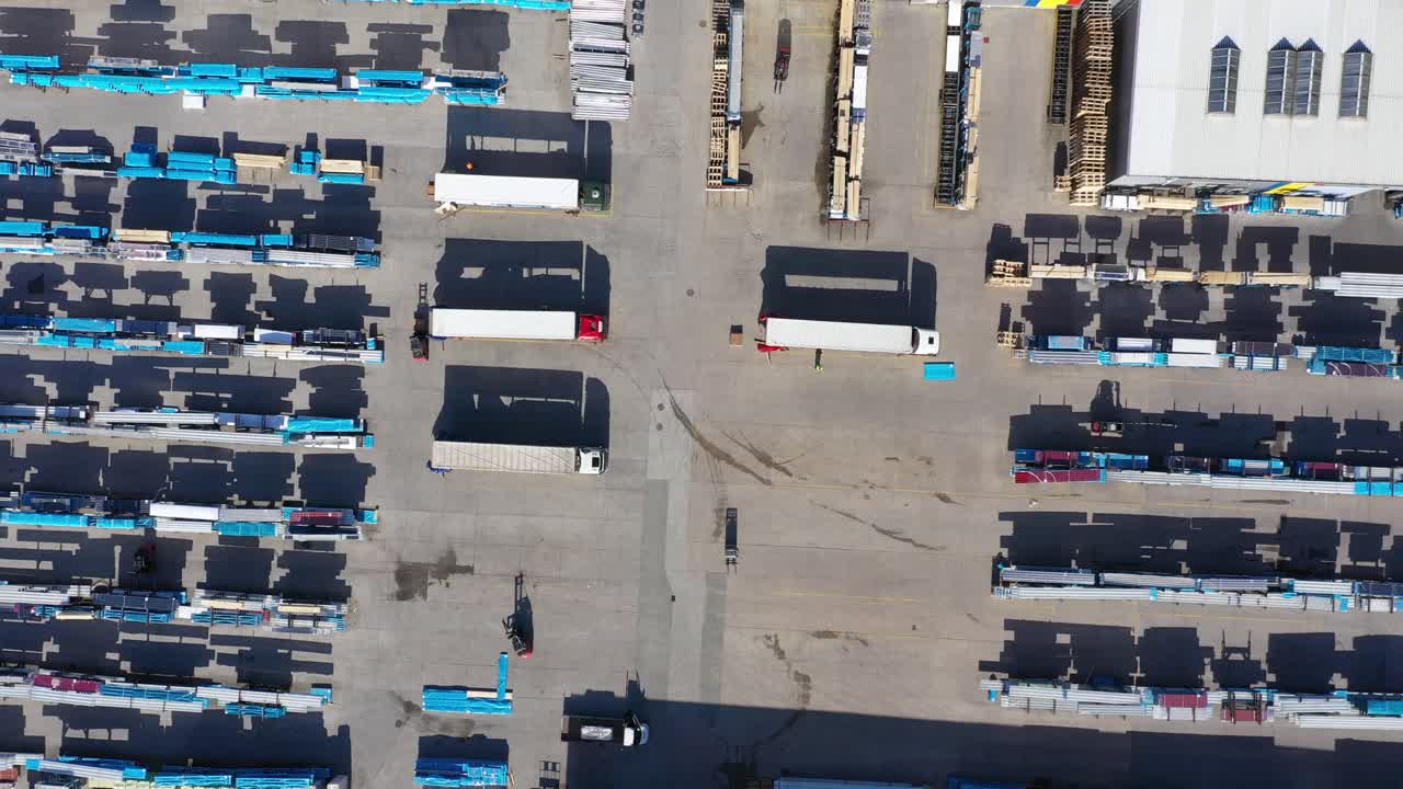 화물 트레일러가 있는 세미 트럭이 물류 공원의 창고를 따라 주차장을 이동하고 있습니다.