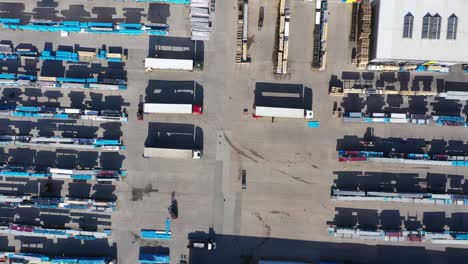 semi truck with cargo trailer is travelling on a parking lot along a warehouse of a logistics park