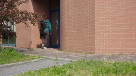 Man-or-person-walking-through-a-residential-area-carrying-an-electric-scooter-cover-and-a-helmet