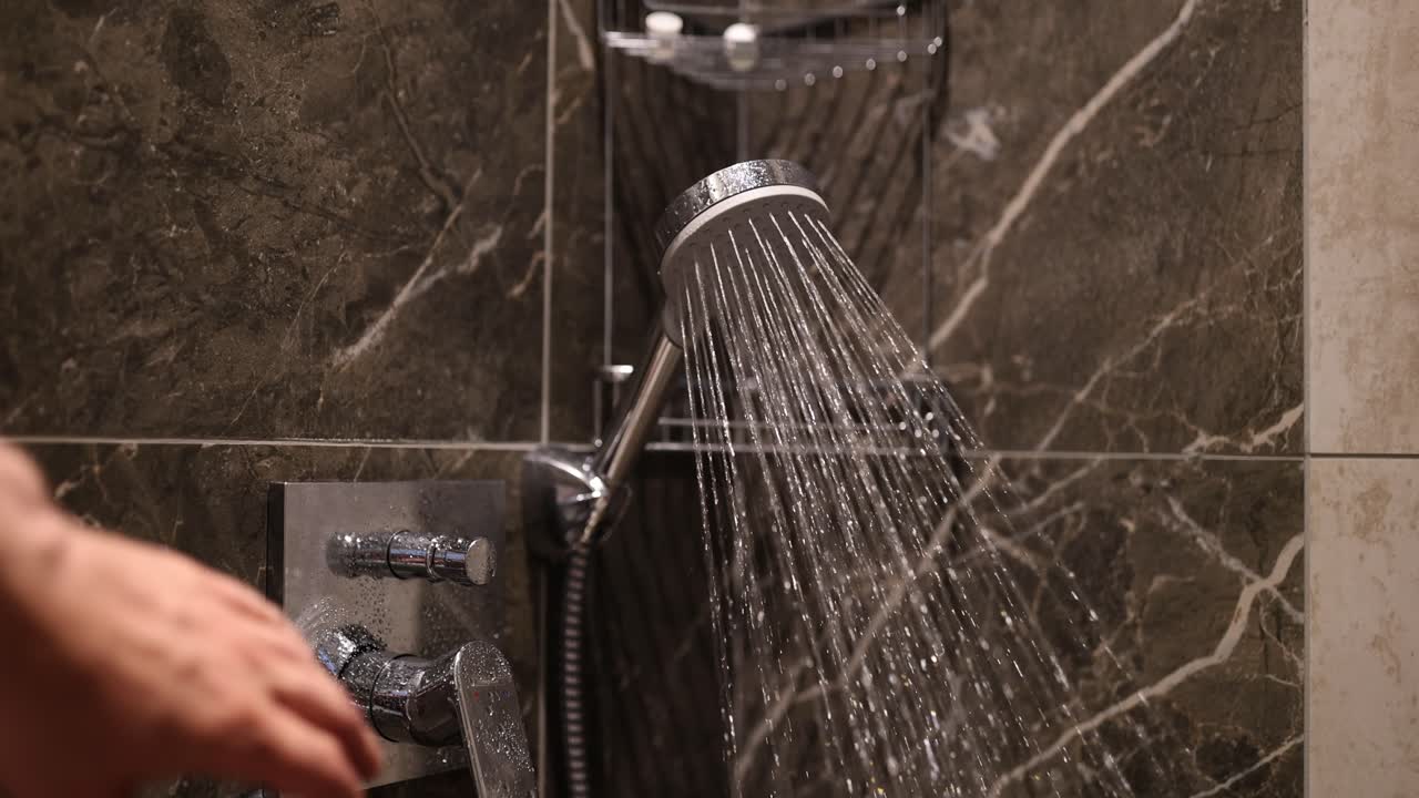Person operating a modern shower in a luxury marble bathroom