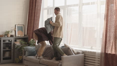 Two Young Happy Men Jumping on Couch at Home