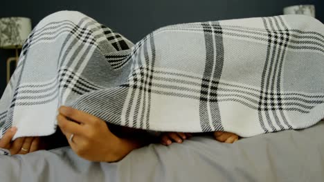 vista frontal de jóvenes padres negros jugando con su hijo en la cama en una casa cómoda 4k