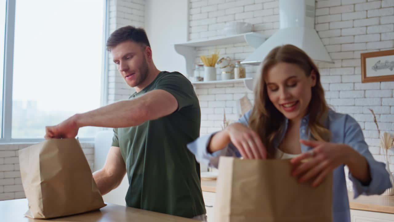 Family couple unpacking groceries kitchen closeup. Pair sharing domestic chores