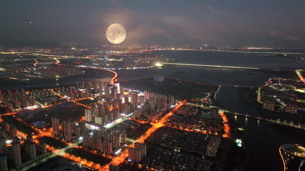 Aerial View of a City at Night with a Full Moon