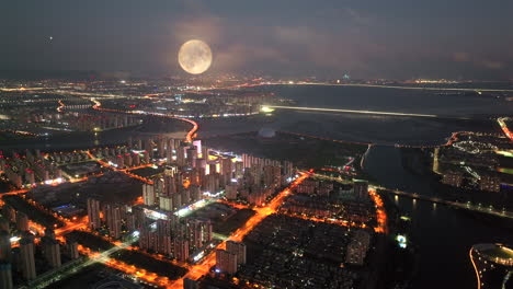 aerial view of a city at night with a full moon