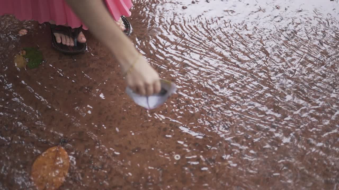Little Girl Playing with Paper Boat in the Rain