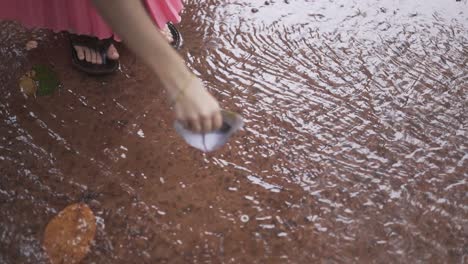 little girl playing with paper boat in the rain