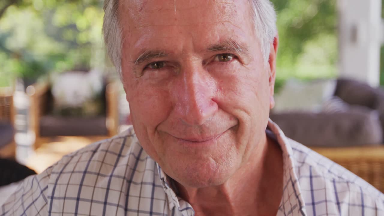 hombre caucásico mayor sonriendo y mirando a la cámara en el jardín