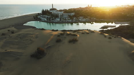 maspalomas dunes, gran canaria: aerial view traveling out over the dunes and spotting the maspalomas pond and the lighthouse