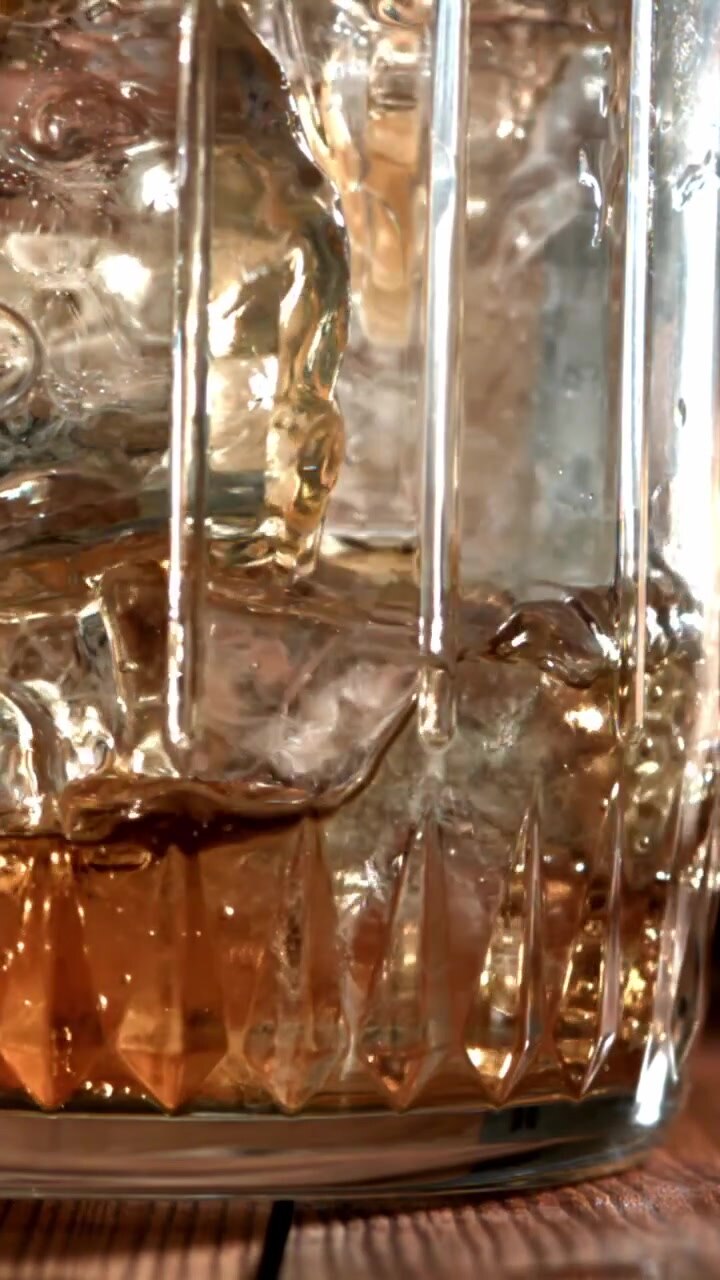 Whiskey dorato versato su cubetti di ghiaccio in un bicchiere