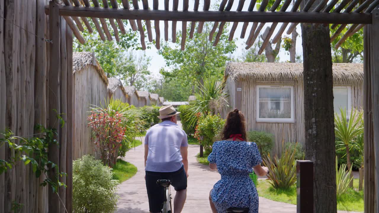 Pareja paseando en bicicleta por el camping con bungalows en Francia