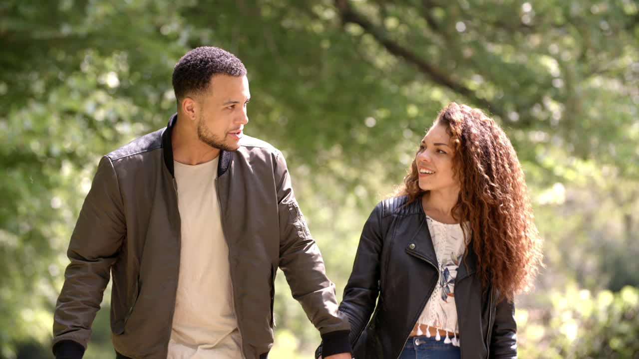 Couple holding hands, walking in a rural setting, front view