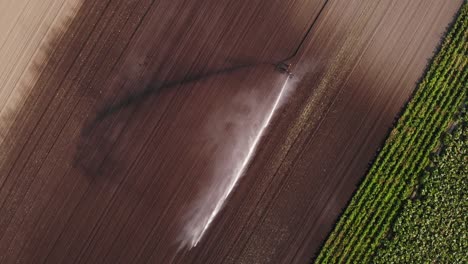 vista de arriba hacia abajo de los rociadores de riego que distribuyen agua en suelo seco de una granja agrícola