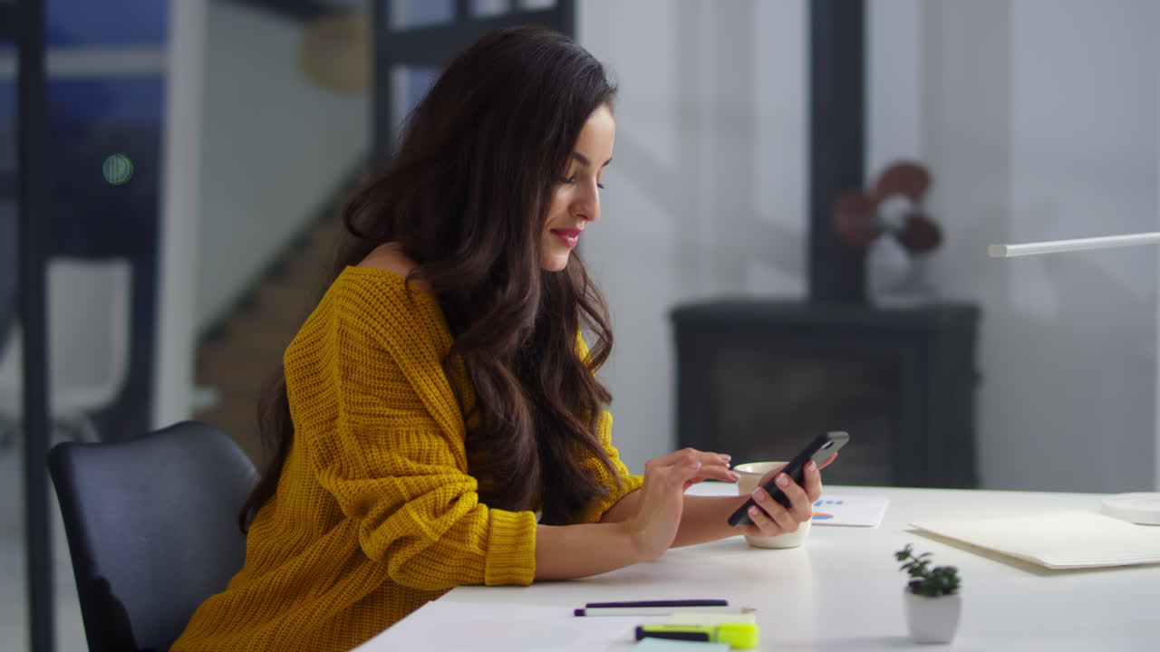Smiling woman browsing internet on smartphone in office