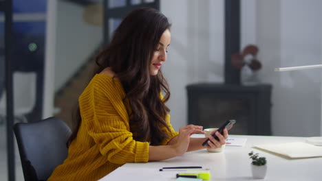 smiling woman browsing internet on smartphone in office