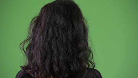 vista trasera de una mujer joven con cabello largo y ondulado pensando y esperando