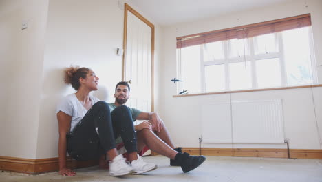 couple sitting on floor in empty room of new home planning design