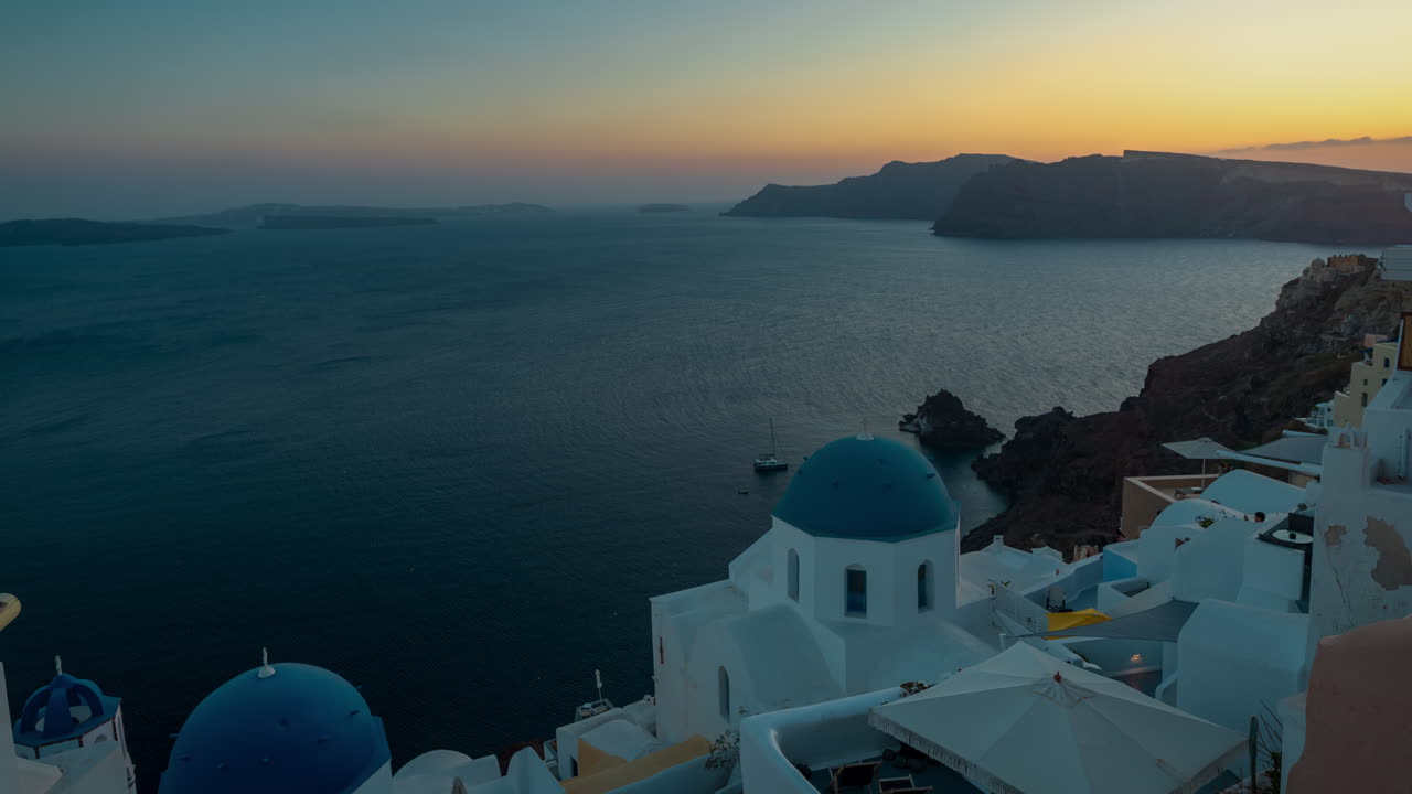 timelapse, puesta de sol sobre la isla de santorini, edificios tradicionales de color azul blanco y el horizonte del mar egeo