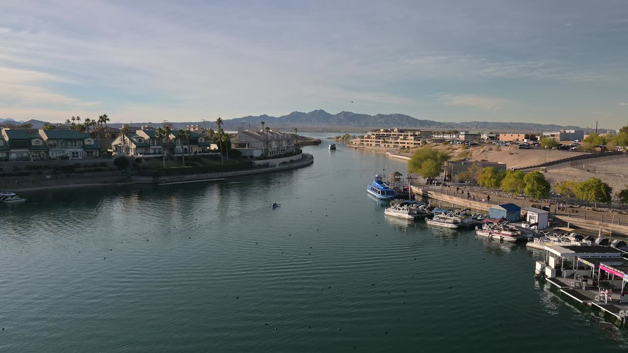 People kayaking down a canal. boats on both sides with mountains in the background on a partly cloudy day. Lake Havasu City Arizona