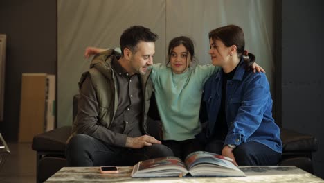 happy parents with a little girl looking through the album together. happy parents with a little girl looking through the album together. high quality footage