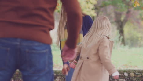 boy and girl playing and having fun with parents throwing autumn leaves in garden