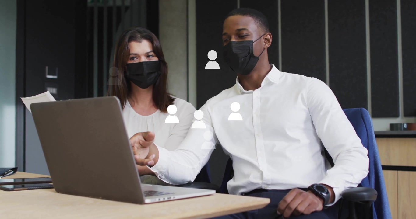Business Colleagues Wearing Face Masks Collaborating on Laptop in Office