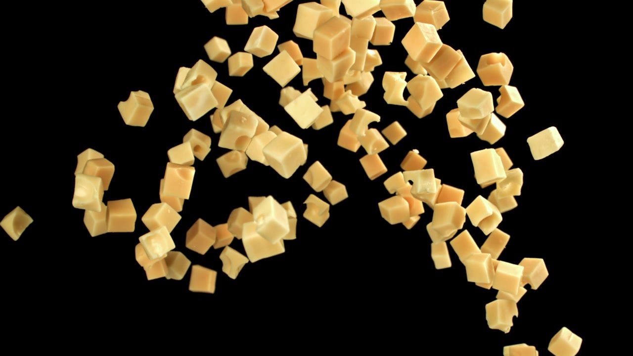 Piccoli cubetti di formaggio che cadono e volano su sfondo nero