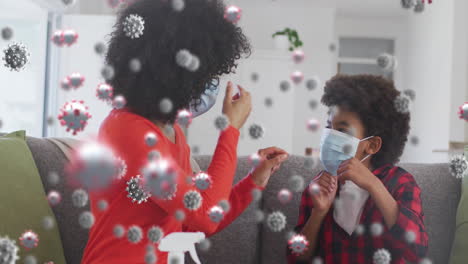 animation of coronavirus cells over biracial mother and son wearing face masks