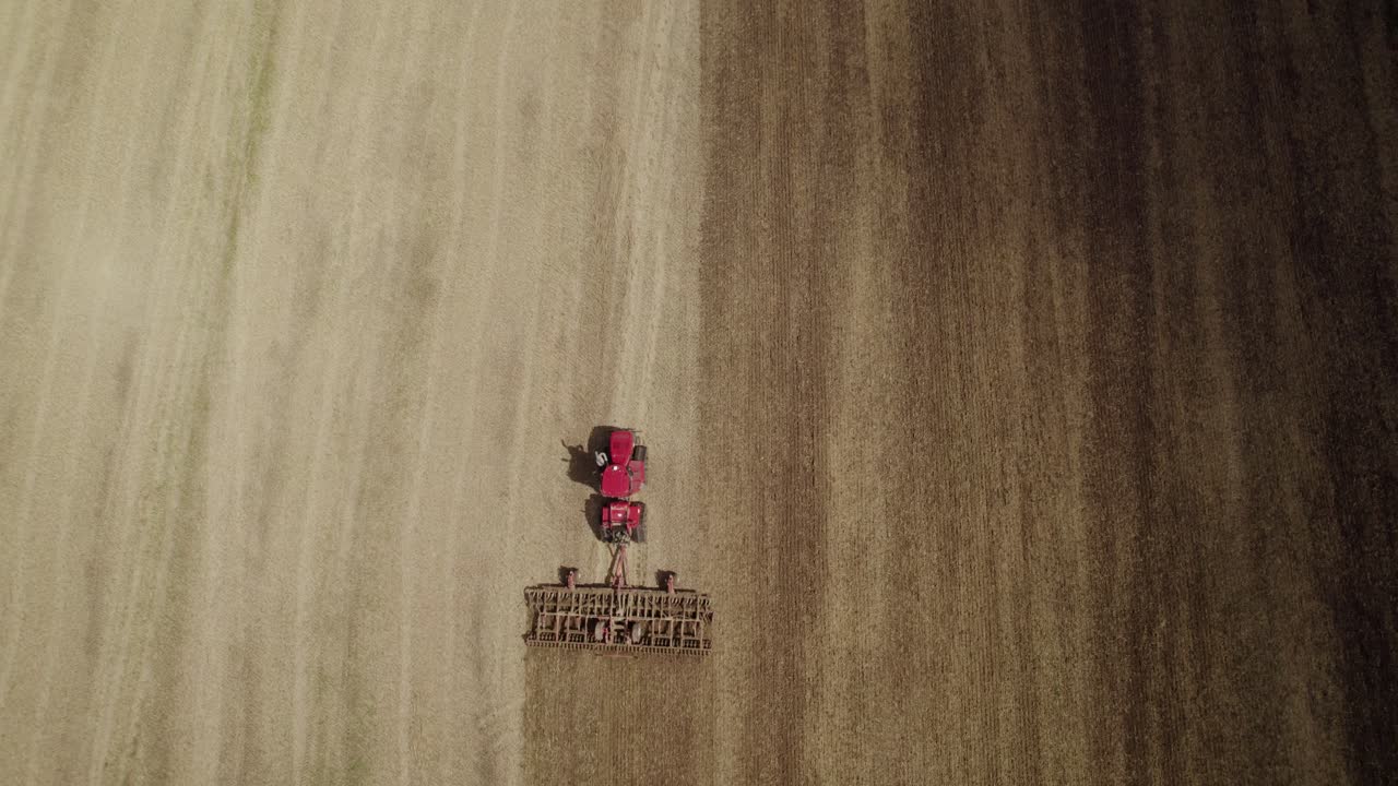 수확 후 토양을 재경작하기 위해 써레 시스템을 당기는 트랙에서 대형 트랙터 위로 공중 하향식 샷