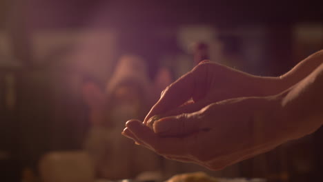 close up on woman's hands rolling raw cookie dough with hands for baking