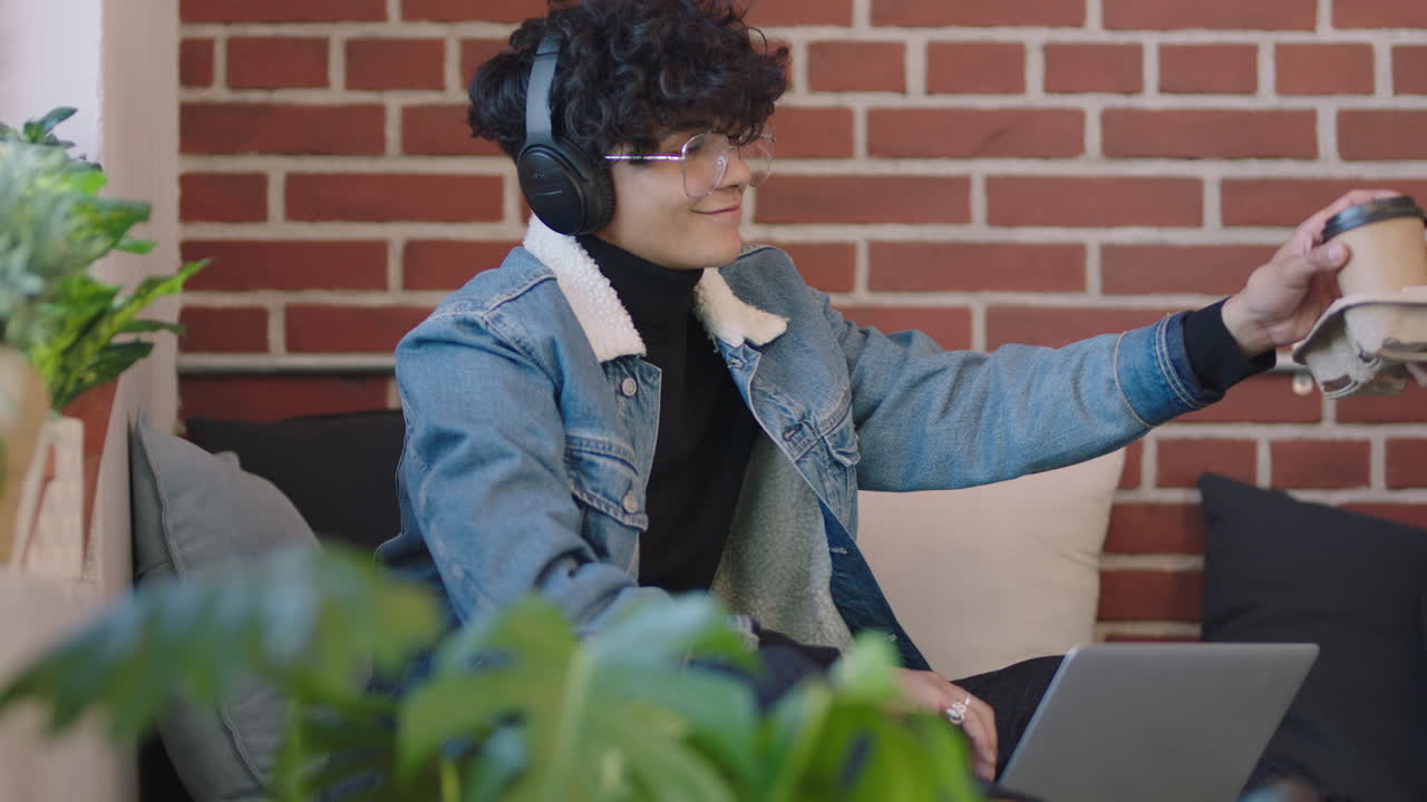 joven estudiante de negocios hispano usando computadora portátil estudiando en línea disfrutando de trabajar escuchando música relajándose en un moderno lugar de trabajo de oficina usando auriculares