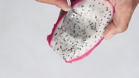 eating a dragon fruit slice with a spoon