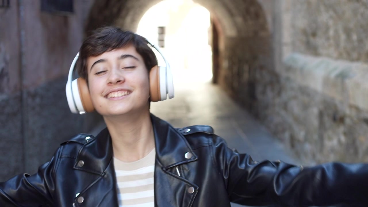Una persona giovane che si gode deliziosamente la musica con le cuffie in un vivace contesto urbano.