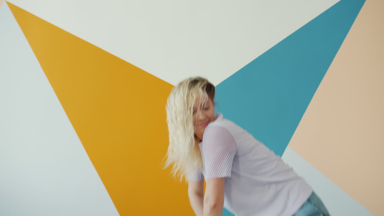 Stylish woman dancing in a colorful room