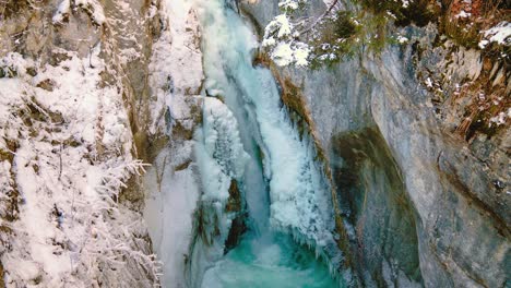 cinemagraph / seamless video loop of the famous tatzlwurm waterfall and river canyon in the bavarian alps in winter in germany. the water is rushing through natural formed rocks with snow and ice. 4k uhd