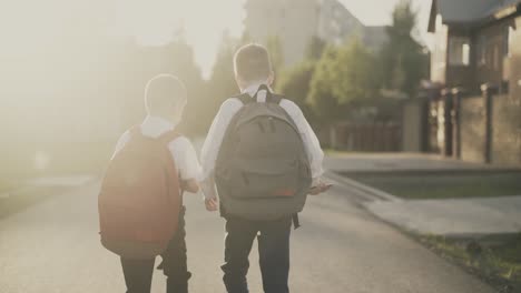 back view two schoolboys return home after classes they talk