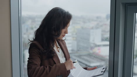 Worried-manager-looking-documents-at-window-close-up.-Woman-reading-papers.