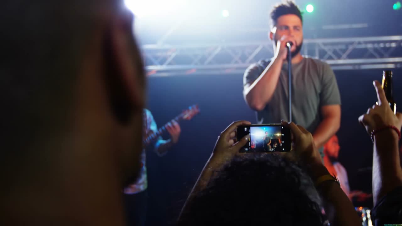 Vocalist taking music stage grabbing mic, singing, guitar riffing and confetti drifting over crowd