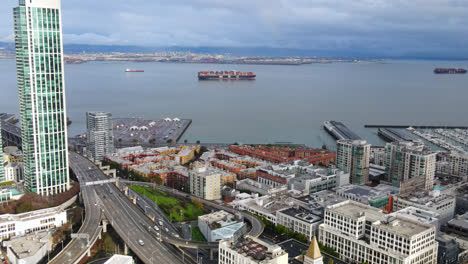 South-Beach-Highway-connecting-San-Francisco-and-Oakland,-South-Beach-harbour-with-container-ships-under-stormy-sky,-California,-USA