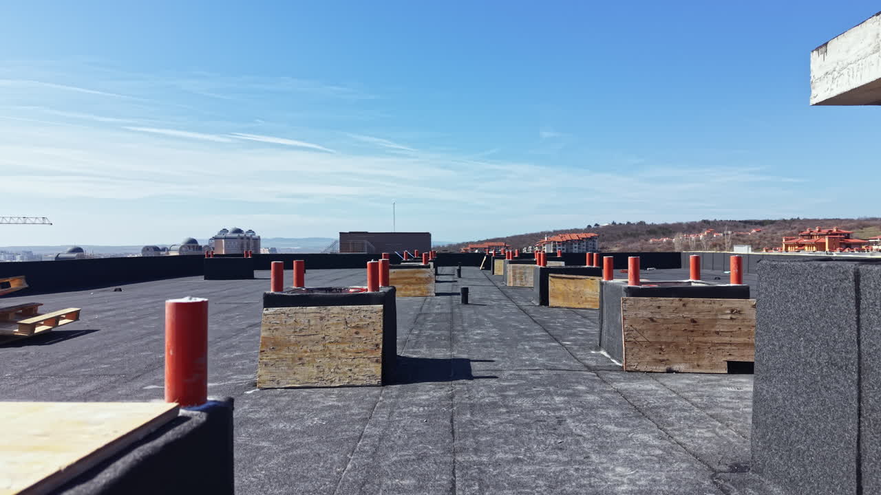 Work taking place on a building roof with materials and tools visible in an outdoor setting during clear weather