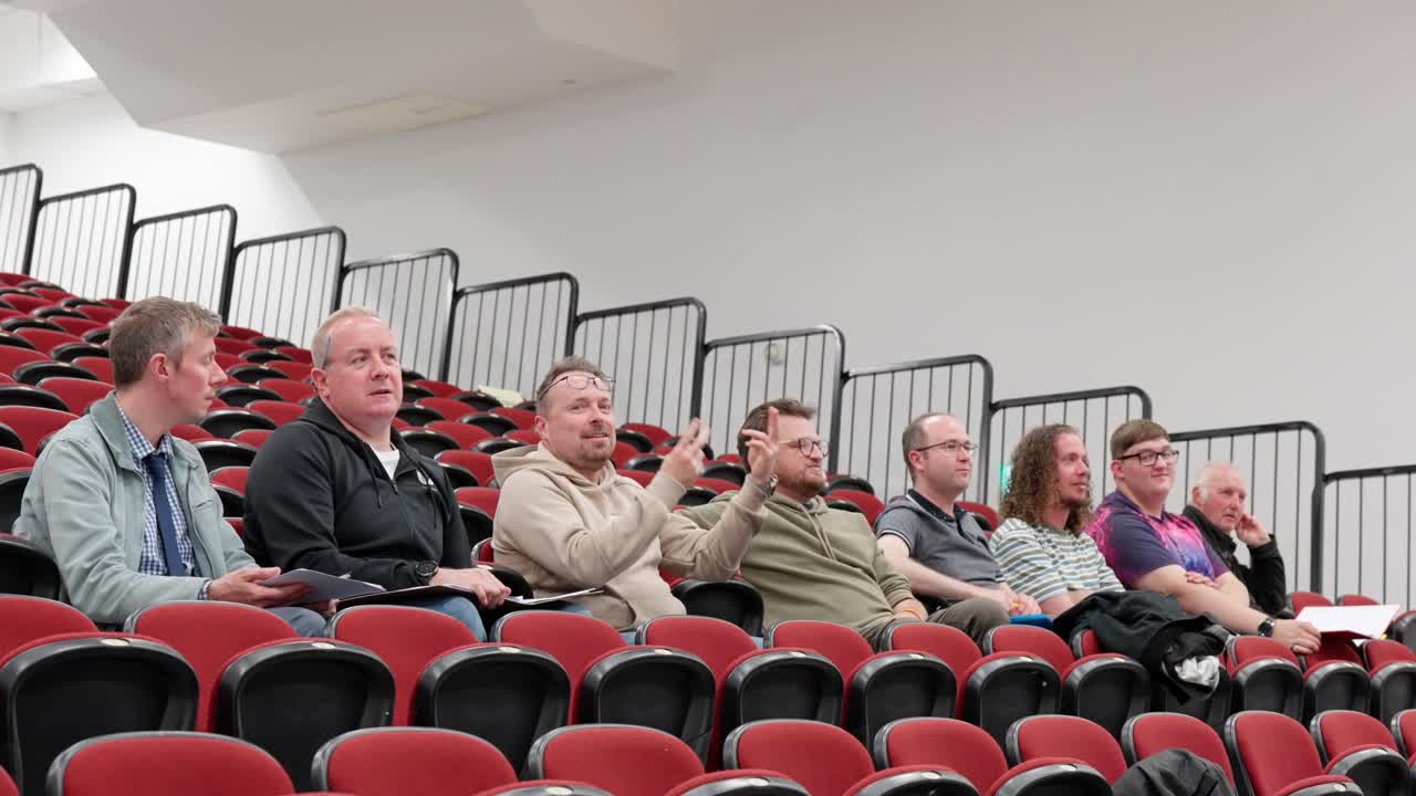 Group of male friends audience members chatting and laughing in auditorium