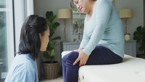 asian female physiotherapist examining female patient holding knee in pain at surgery