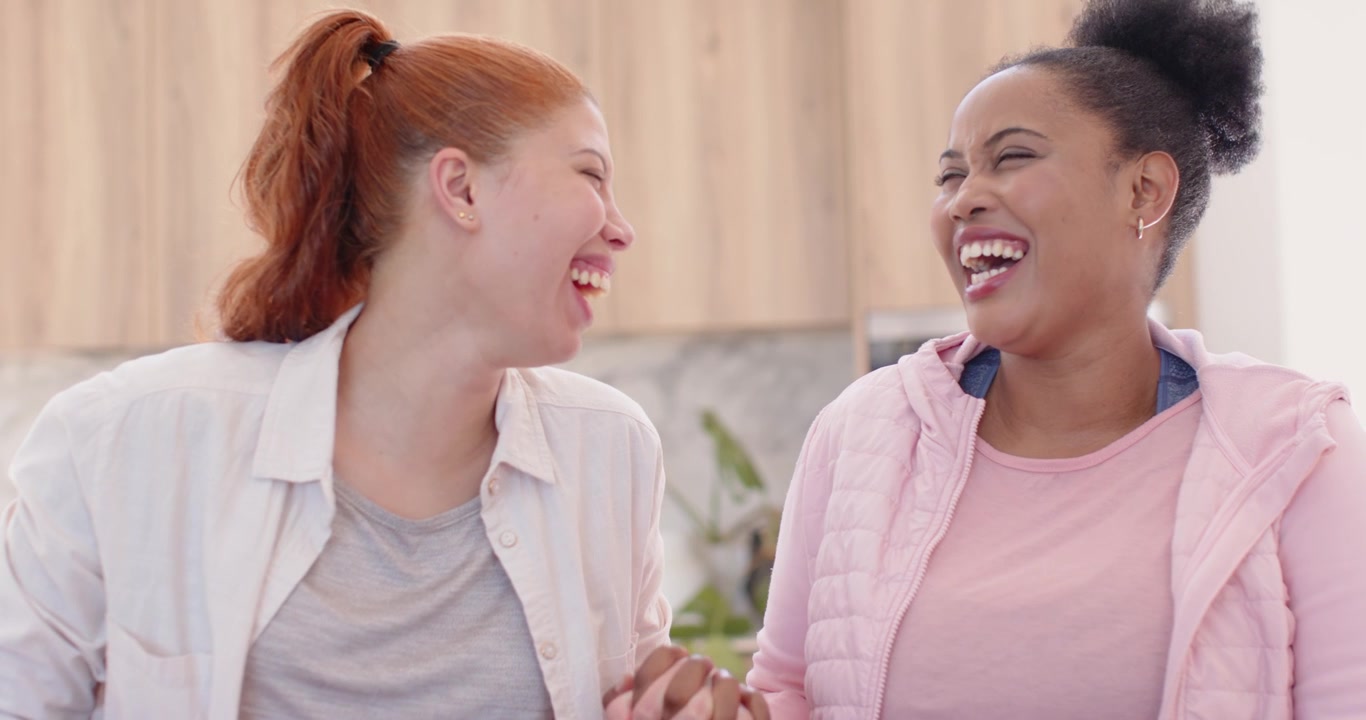 Amiche afroamericane che si tengono per mano, sfiorandosi le dita, ridendo in cucina, smartwatch