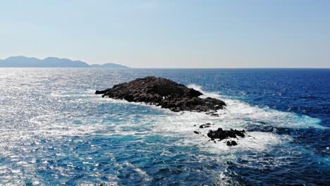 olas espumosas azules rompiendo en las rocas en la playa de jerusalén en grecia - toma aérea de drones