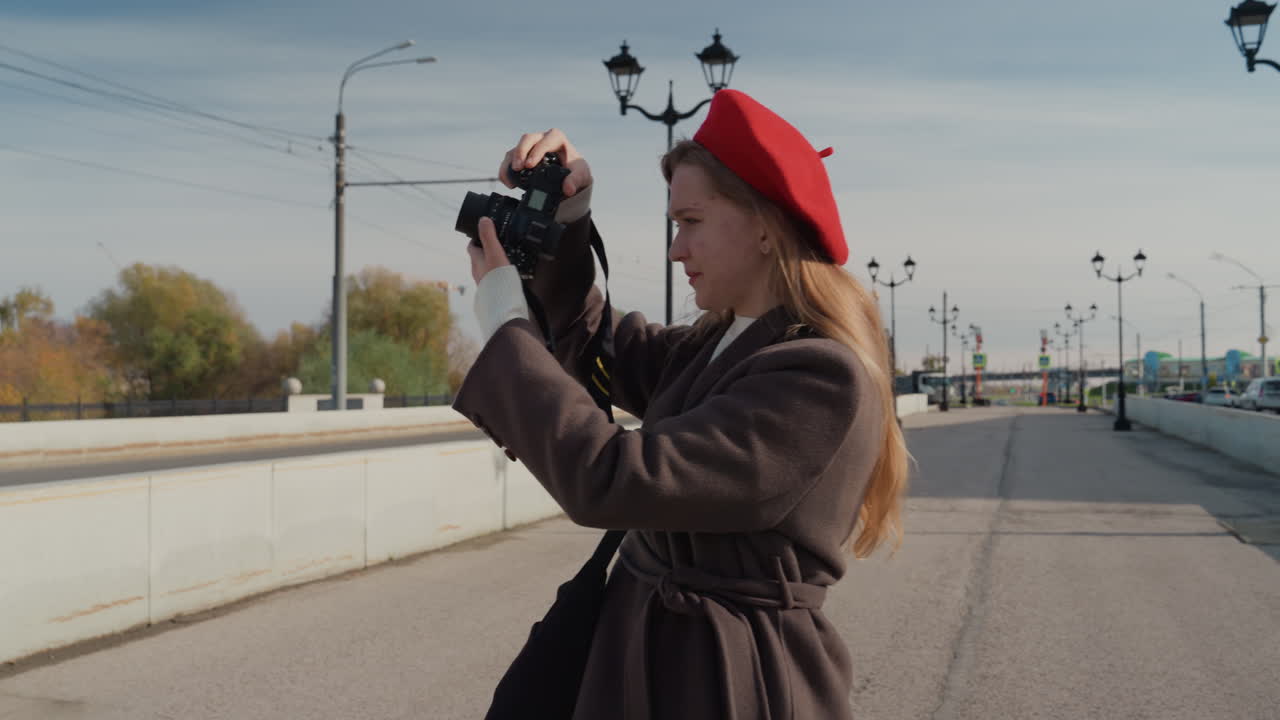 Kamerasıyla şehir manzarasını keşfeden kadın. Şehir sokaklarının ve ufuk çizgisinin fotoğraflarını çeken kadın fotoğrafçı. Kahverengi paltolu kadın, kamerasıyla kentsel çevrenin doğal anlarını yakalıyor.