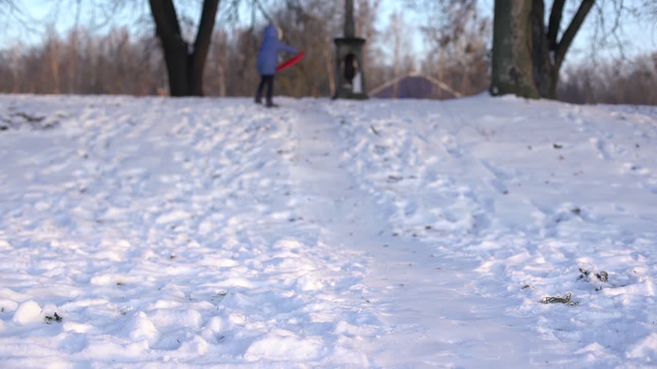 어린 소녀가 얼음 매에서 슬라이드를 오르고, 겨울