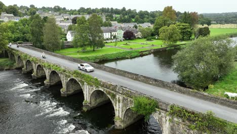 kilkenny ireland inistioge aerial static of the river and bridge with the village park on a summer morning with a cycle race crossing the bridge